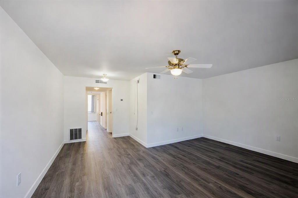 An empty room with white walls, dark wood-look flooring, and a ceiling fan — 911 WASHINGTON AVENUE UNIT 209, LARGO, FL