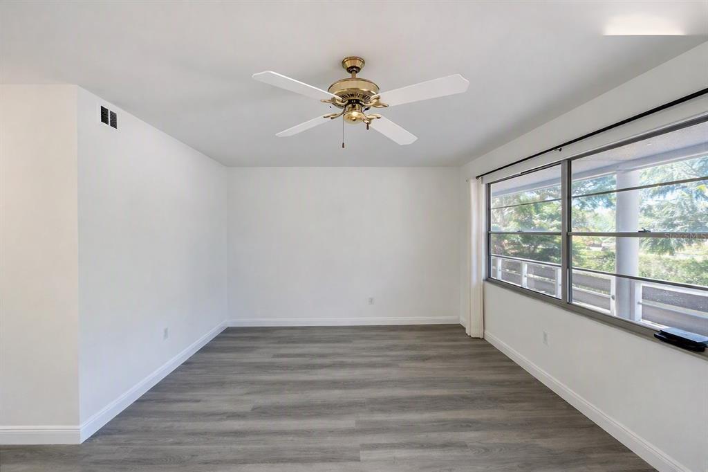 An empty room with gray wood-look flooring, white walls, and a ceiling fan — 911 WASHINGTON AVENUE UNIT 209, LARGO, FL