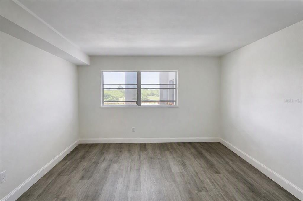 An empty room with white walls, gray wood-look flooring, and a single window — 911 WASHINGTON AVENUE UNIT 209, LARGO, FL