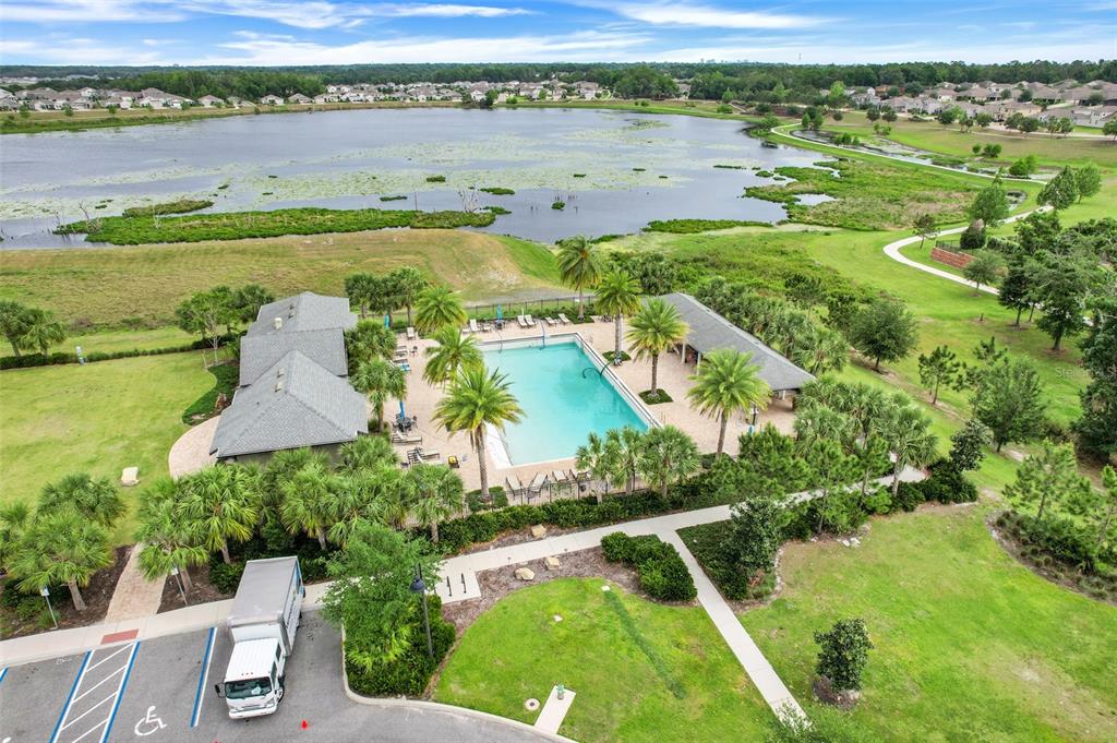 An aerial view shows a community swimming pool and clubhouse next to a large lake — 1817 LAKE SIMS PARKWAY, OCOEE, FL