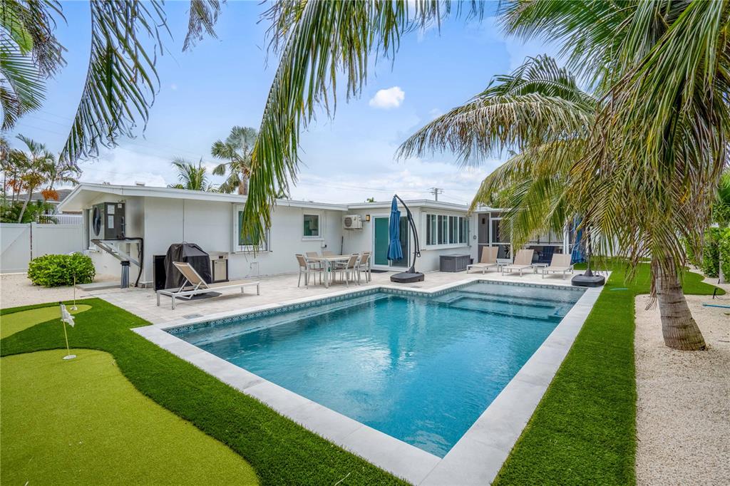 A backyard features a swimming pool, a putting green, and a patio with outdoor furniture — 306 66TH STREET, HOLMES BEACH, FL
