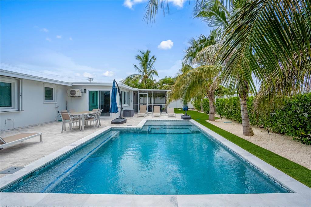 A rectangular swimming pool sits on a patio next to a house with palm trees — 306 66TH STREET, HOLMES BEACH, FL