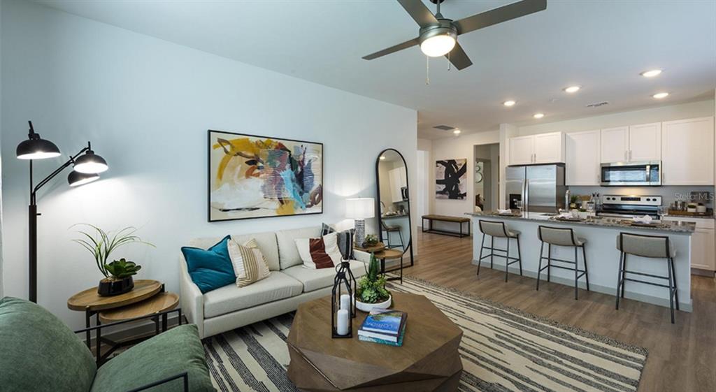 An open-concept living room and kitchen featuring a sofa, coffee table, and breakfast bar — 4980 RED MAPLE LANE UNIT C1, WILDWOOD, FL