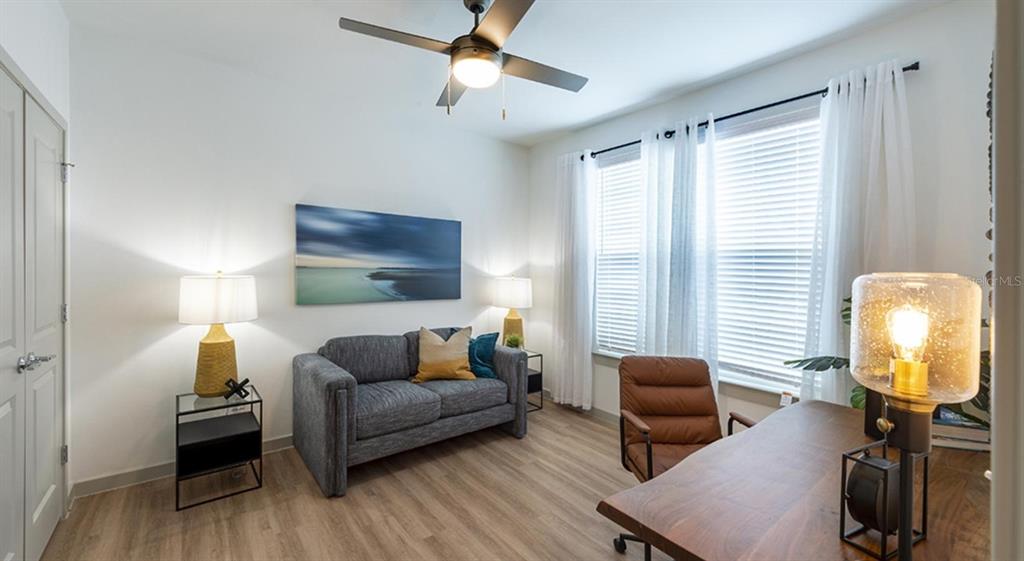 A home office features a gray sofa, a wooden desk, and a ceiling fan — 4980 RED MAPLE LANE UNIT C1, WILDWOOD, FL