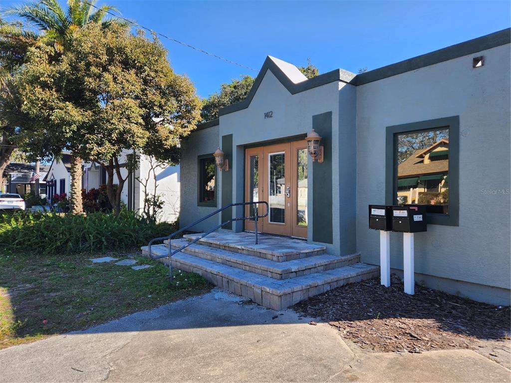 The exterior of a single-story building features a central entrance with steps and a railing — 1412 E ROBINSON STREET, ORLANDO, FL