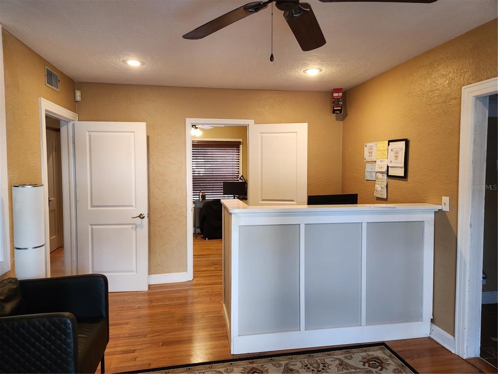 A reception desk with frosted panels sits in a room with tan walls and hardwood floors — 1412 E ROBINSON STREET, ORLANDO, FL