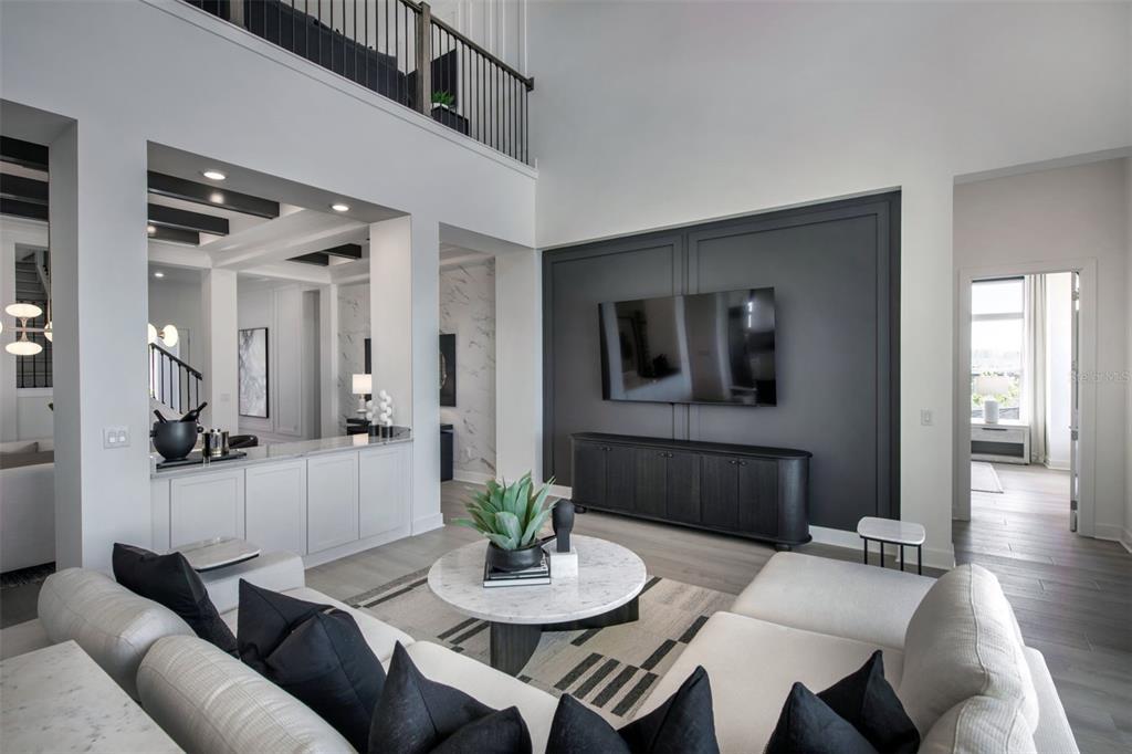 A modern living room features a dark accent wall with a mounted television and white furniture — 35626 COHAGEN TRAIL, ZEPHYRHILLS, FL