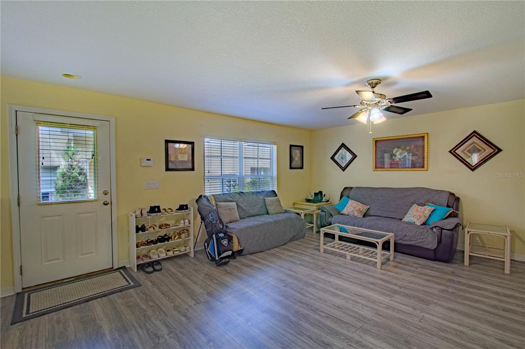 A living room features light yellow walls, wood-look flooring, two sofas, and a ceiling fan — 10917 BRICKSIDE COURT, RIVERVIEW, FL