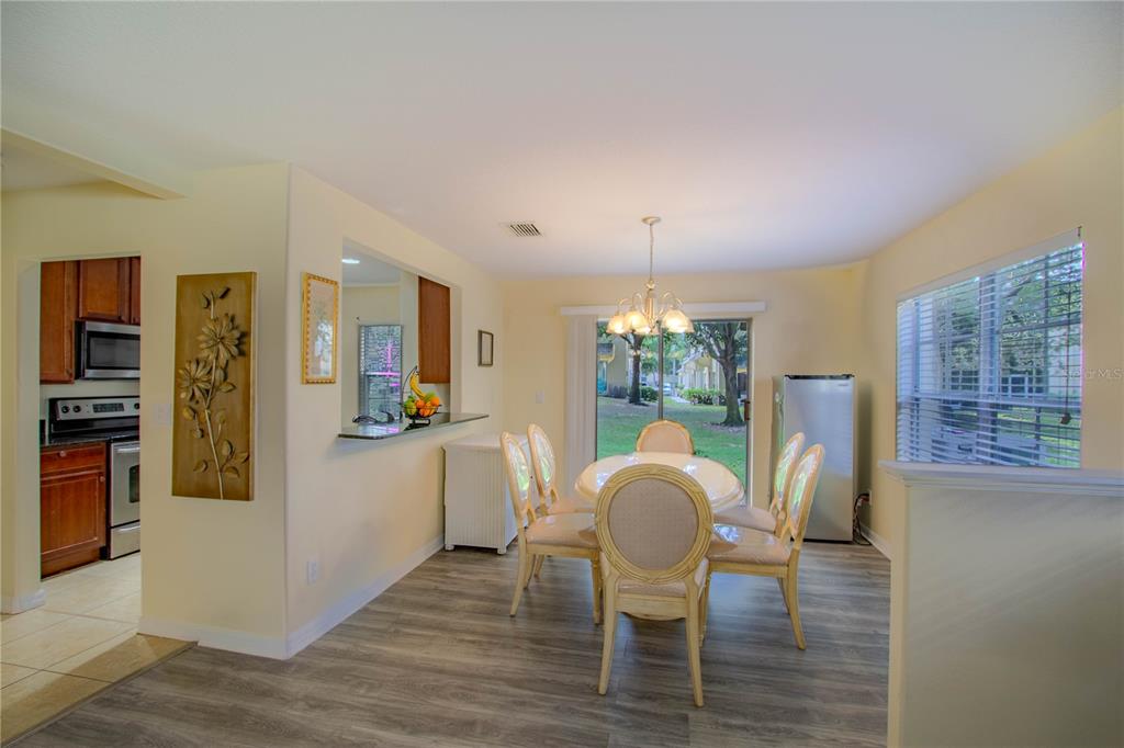 A dining area with a round table, chairs, sliding glass doors, and a kitchen pass-through — 10917 BRICKSIDE COURT, RIVERVIEW, FL