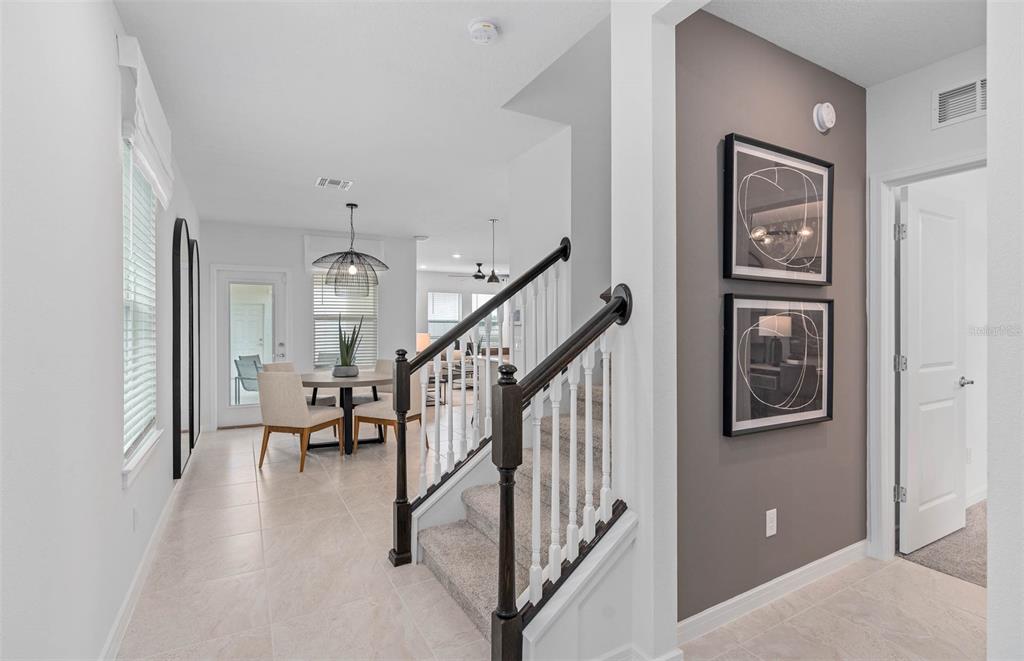 A view from a hallway toward a dining area with stairs and a gray accent wall — 2209 SOUTHBURY DRIVE, KISSIMMEE, FL