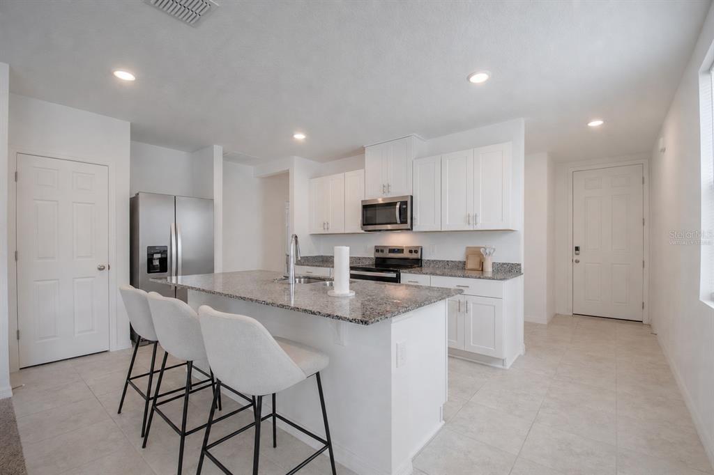 A white door with a smart lock stands at the end of a tiled entryway — 3181 VICEROY COURT, KISSIMMEE, FL