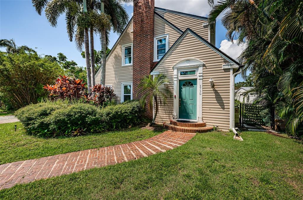 A two-story house with beige siding, a brick chimney, and a teal front door — 3730 FOSTER HILL DRIVE N, ST PETERSBURG, FL