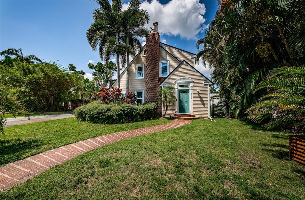 A two-story house with beige siding, a brick chimney, and a brick walkway — 3730 FOSTER HILL DRIVE N, ST PETERSBURG, FL
