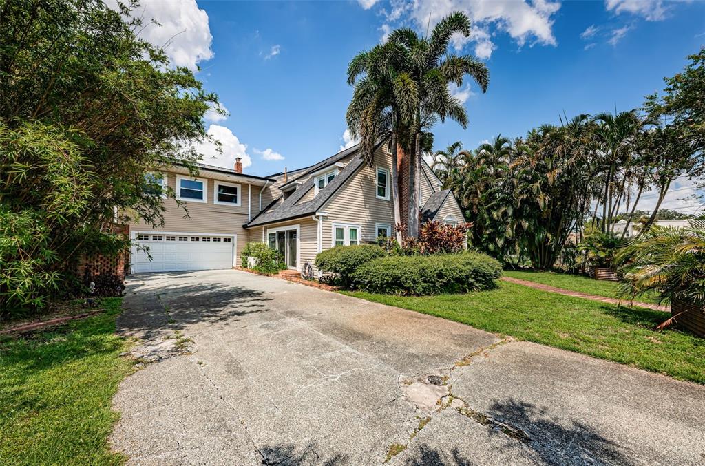 A two-story house with beige siding, a white garage door, and a palm tree — 3730 FOSTER HILL DRIVE N, ST PETERSBURG, FL