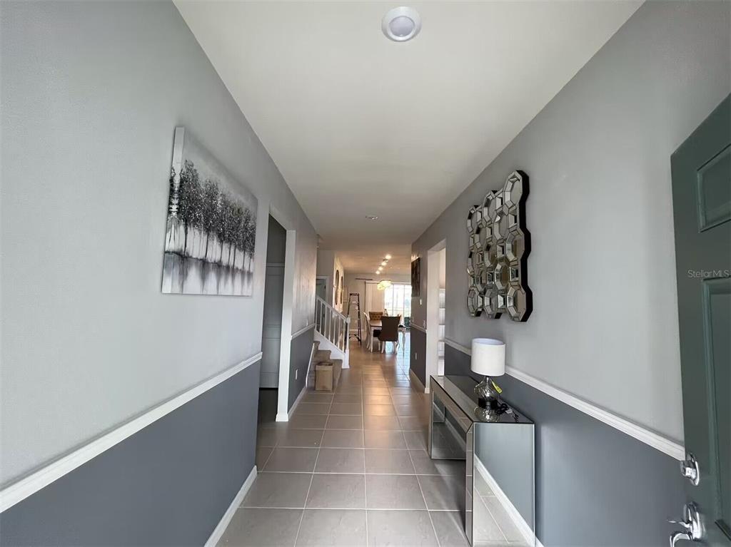 A tiled entryway features gray walls with white wainscoting, a mirrored console table, and wall art — 3012 MAHALO DRIVE, DAVENPORT, FL