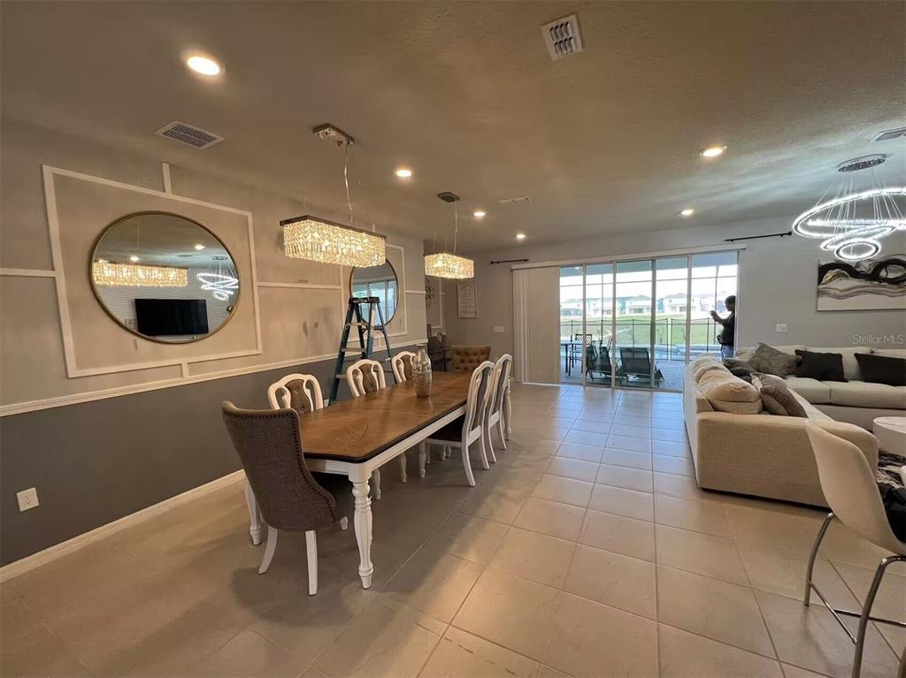 A dining area with a wooden table and crystal chandeliers opens into a living room — 3012 MAHALO DRIVE, DAVENPORT, FL