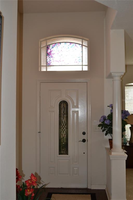 An entryway features a white front door with a stained glass insert and arched transom window — 659 WINTHROP DRIVE, SPRING HILL, FL