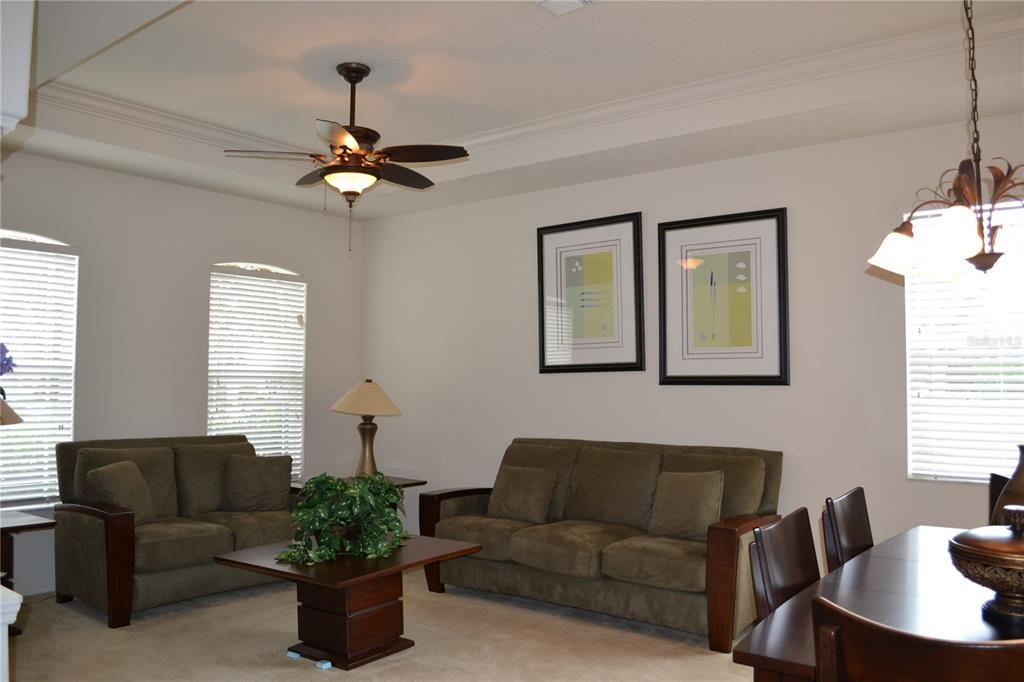 A living room with a ceiling fan, two brown sofas, and framed wall art — 659 WINTHROP DRIVE, SPRING HILL, FL