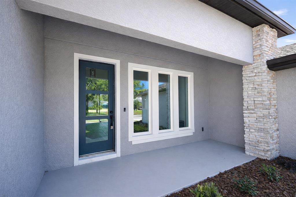 A dark blue front door sits beside a three-pane window on a gray exterior wall — 45 ROYAL OAK DRIVE, PALM COAST, FL