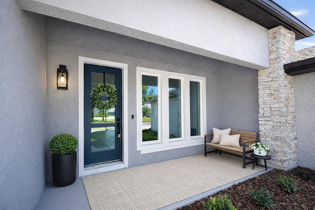 A gray exterior entryway features a dark blue glass-paneled door and a triple-pane window — 45 ROYAL OAK DRIVE, PALM COAST, FL
