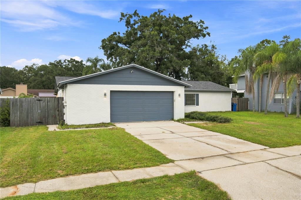 A single-story house with a white brick exterior, blue garage door, and a concrete driveway — 4313 FOXGLEN LANE, TAMPA, FL