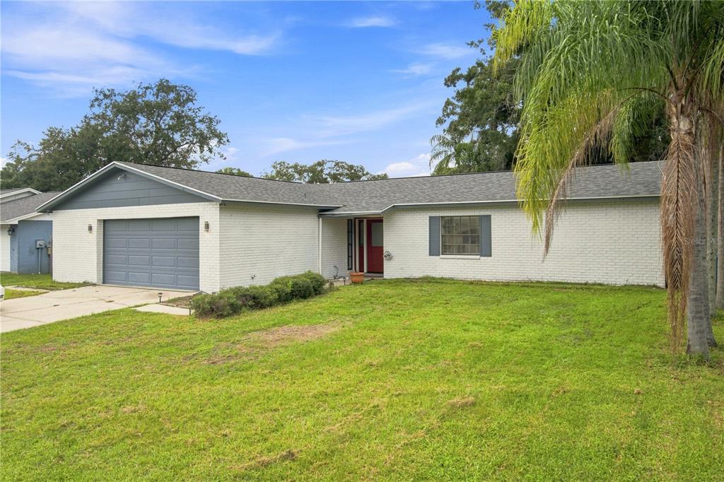 A single-story house with a white brick exterior, gray garage door, and a red front door — 4313 FOXGLEN LANE, TAMPA, FL