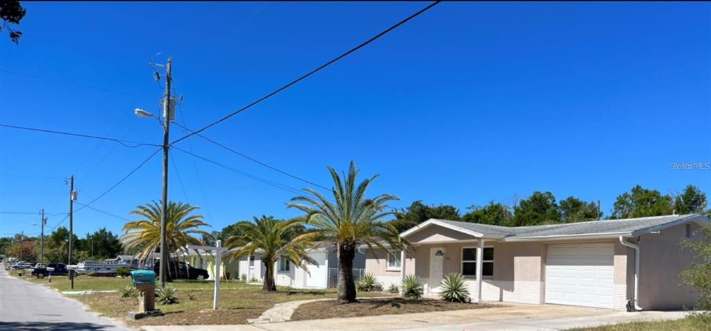 A single-story house with a white garage door and palm trees in the front yard — 7407 UNIVERSITY DRIVE, HUDSON, FL