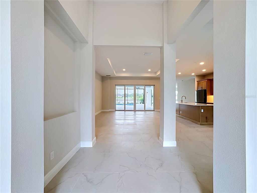 A view from a hallway looking into an open living area with tile flooring — 12418 STONEGATE TRAIL, PARRISH, FL