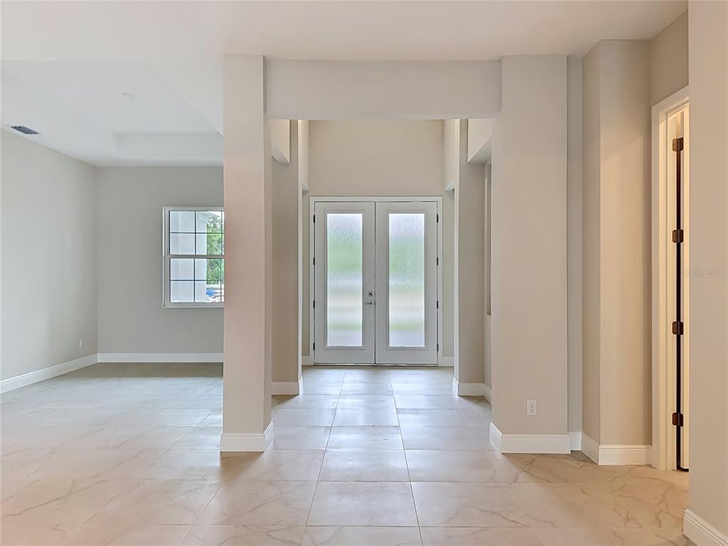 An entryway with light-colored tile flooring, a double glass door, and neutral wall paint — 12418 STONEGATE TRAIL, PARRISH, FL