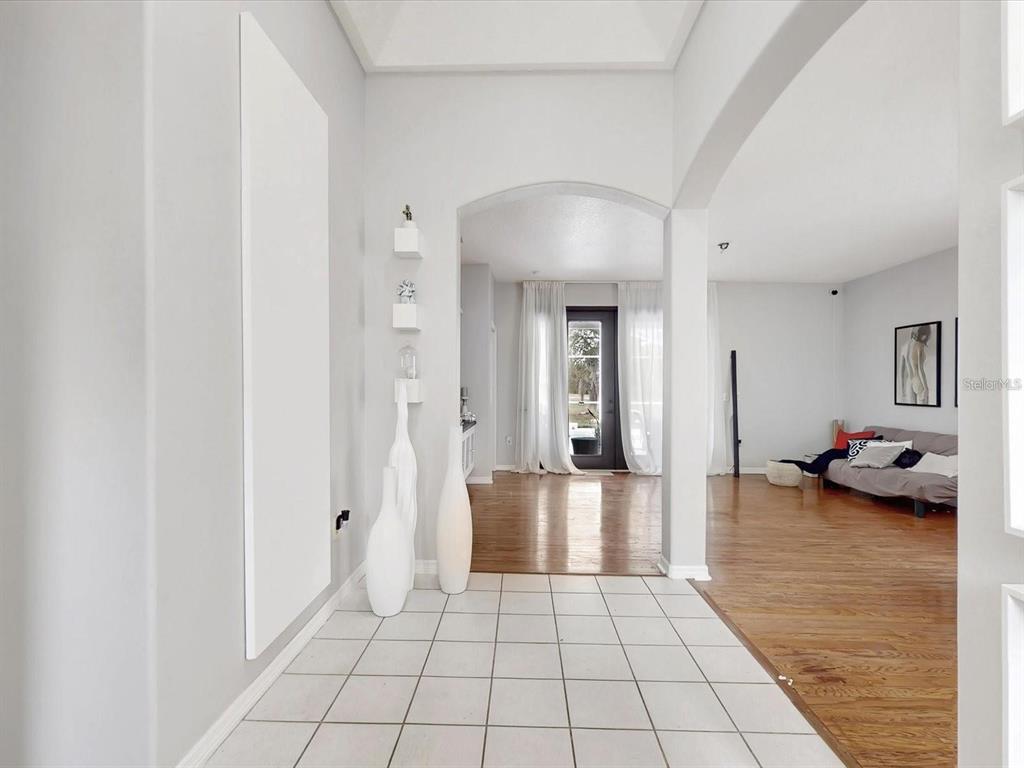 A tiled entryway leads to a living area with hardwood floors and an arched doorway — 1718 GOLFVIEW DRIVE, KISSIMMEE, FL