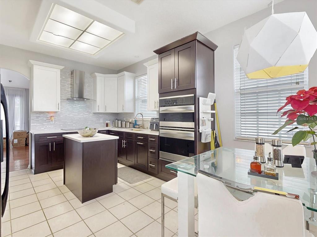 A kitchen features dark and white cabinetry, stainless steel appliances, and a central island — 1718 GOLFVIEW DRIVE, KISSIMMEE, FL