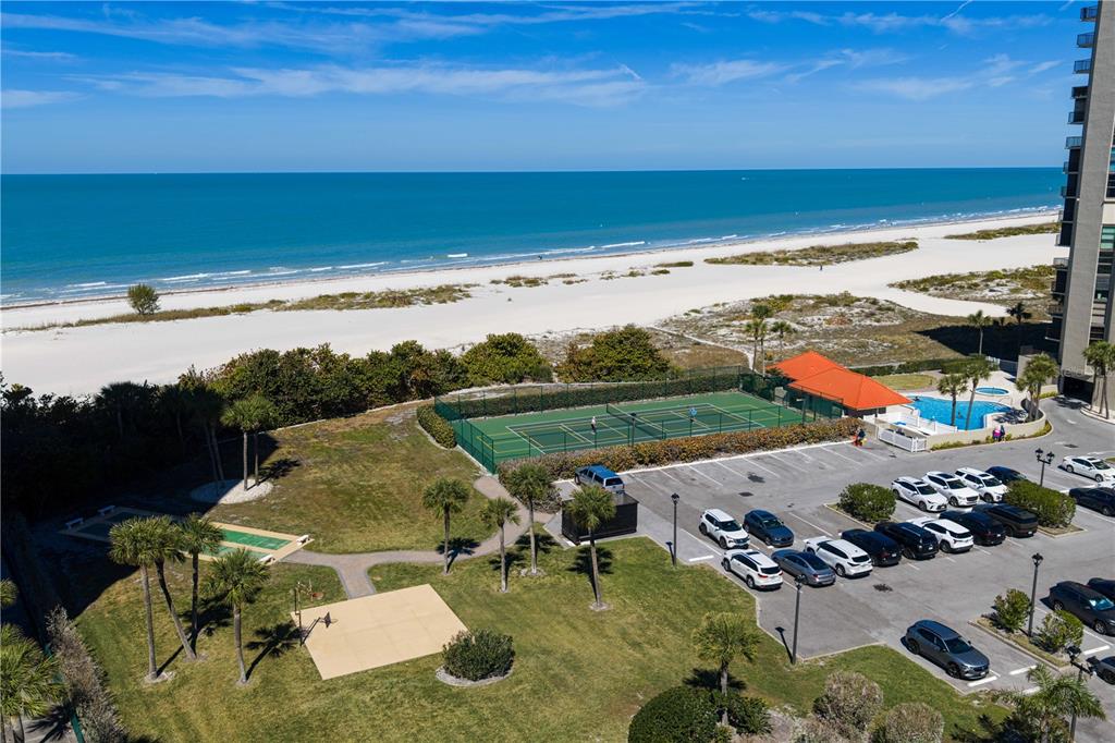 A balcony with outdoor furniture and a crab wall decoration overlooks a sandy beach — 1290 GULF BOULEVARD UNIT 1002, CLEARWATER, FL