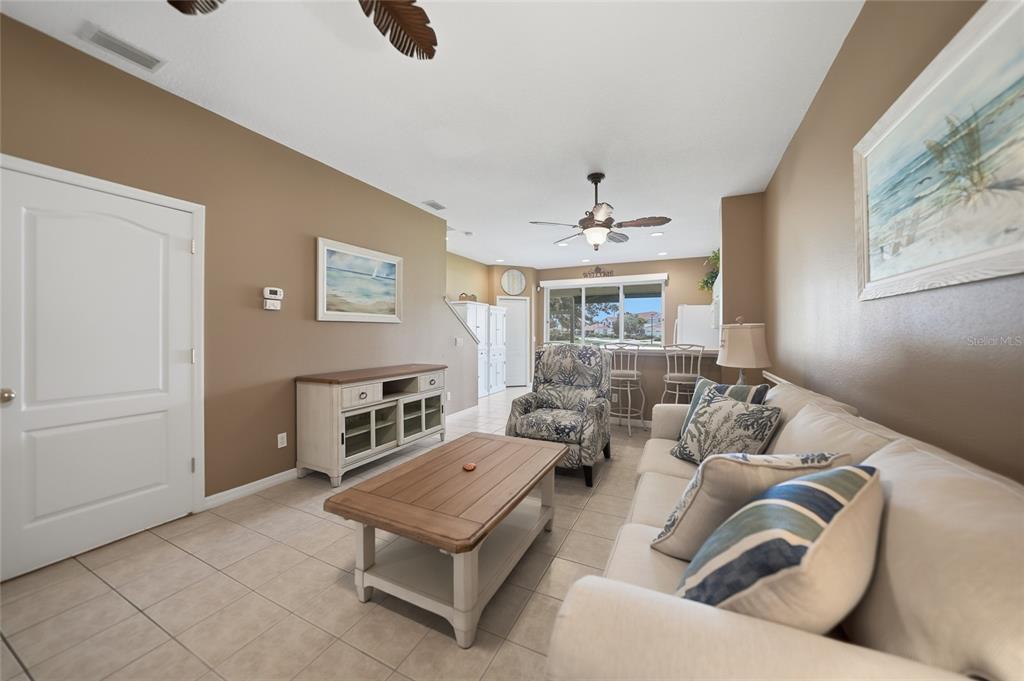 A living room features beige walls, tile flooring, a white media console, and a sofa — 2330 FELICITY PLACE, NORTH PORT, FL