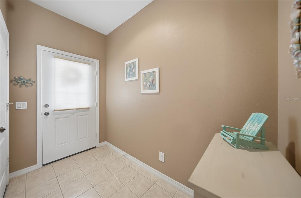 An entryway features tan walls, tile flooring, a white door, and a small decorative chair — 2330 FELICITY PLACE, NORTH PORT, FL