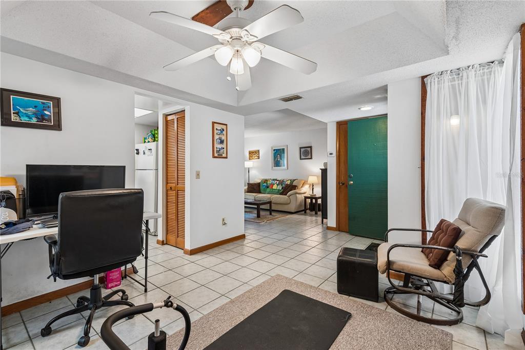 A room with white tile floors, a ceiling fan, a desk, and a view into another living area — 13 PINEHURST PLACE UNIT 13, PALM COAST, FL