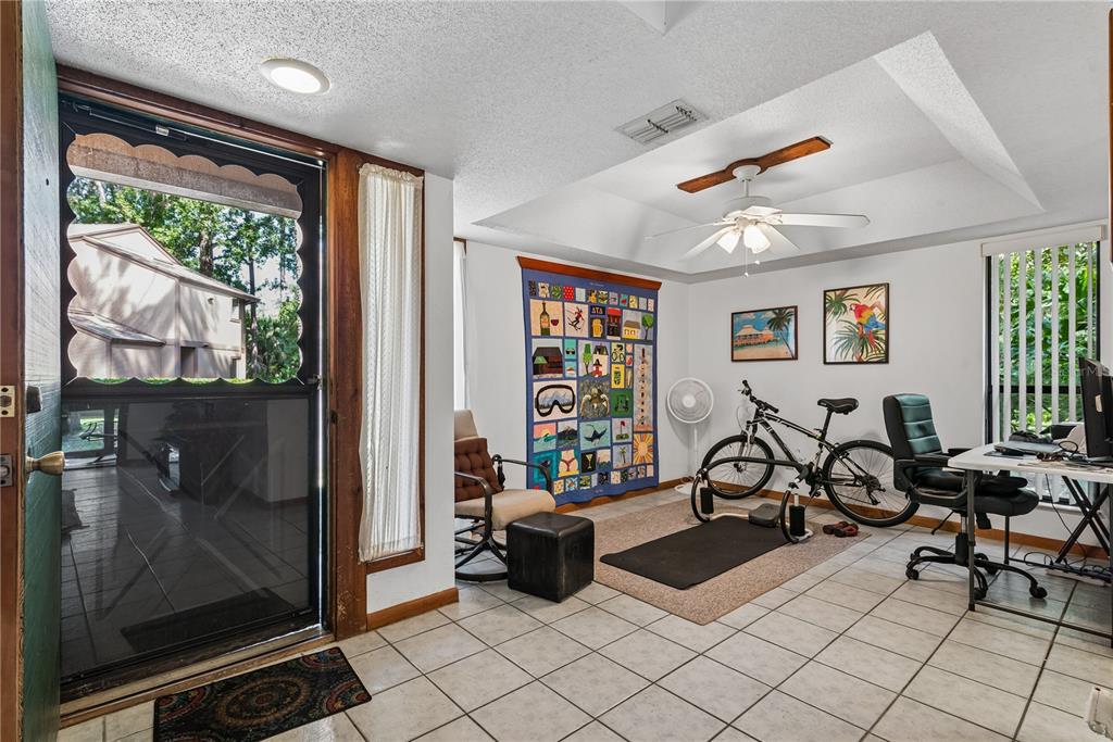 A tiled room with a ceiling fan, exercise bike, desk, and a wall-mounted quilt — 13 PINEHURST PLACE UNIT 13, PALM COAST, FL