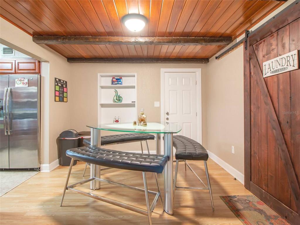 A dining area features a glass table, two black benches, and a wood-paneled ceiling — 1245 CATALPA LN UNIT 1, ORLANDO, FL