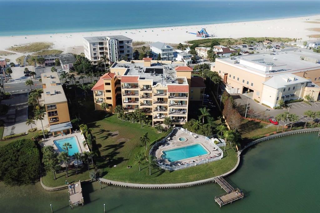 A balcony with a glass-topped dining table and chairs overlooking a waterway and buildings — 10315 GULF BOULEVARD UNIT 409, TREASURE ISLAND, FL