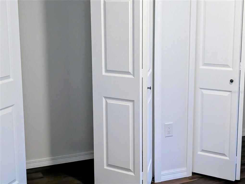 A room features white paneled doors, dark wood flooring, and a wall-mounted electrical outlet — 776 E BROADWAY STREET, OVIEDO, FL