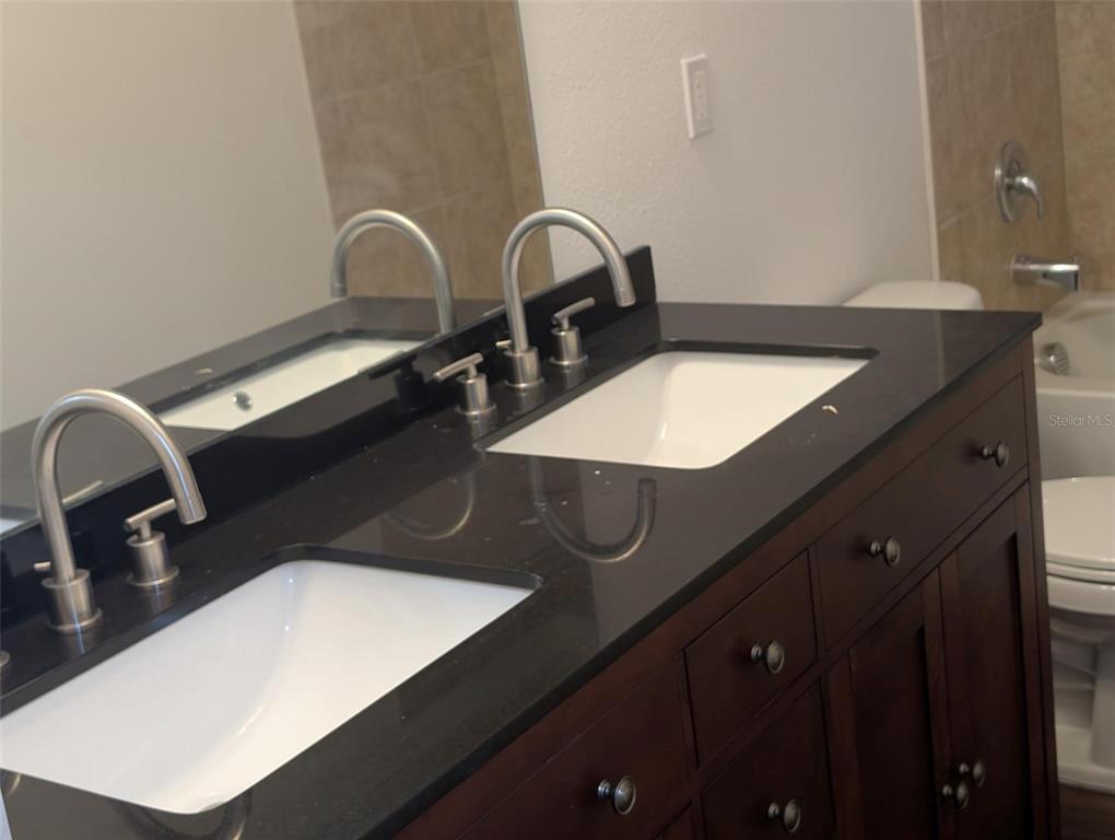 A bathroom vanity features a dark countertop, dual white sinks, and dark wood cabinetry — 776 E BROADWAY STREET, OVIEDO, FL