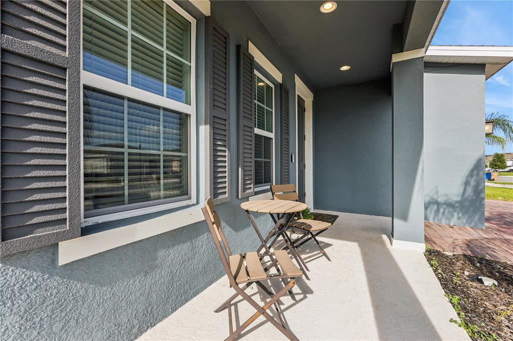 A covered front porch features a small wooden table and two chairs against a house — 5592 VIGO LOOP, ST CLOUD, FL