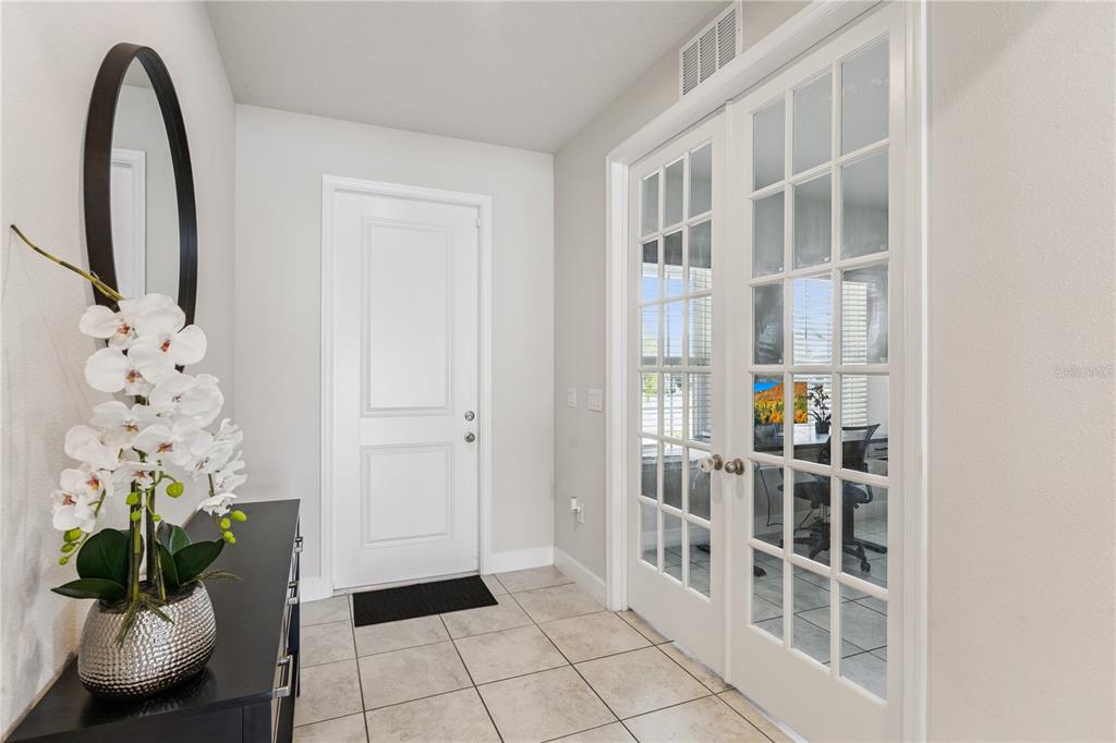 An entryway features tile flooring, a white door, and glass-paned French doors leading to an office — 5592 VIGO LOOP, ST CLOUD, FL