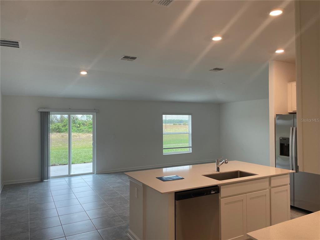 A kitchen island with a sink and dishwasher overlooks a living area with tile floors — 612 DARING DRIVE, DAVENPORT, FL