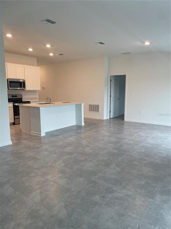 A kitchen with white cabinets, a central island, and gray tile flooring — 612 DARING DRIVE, DAVENPORT, FL
