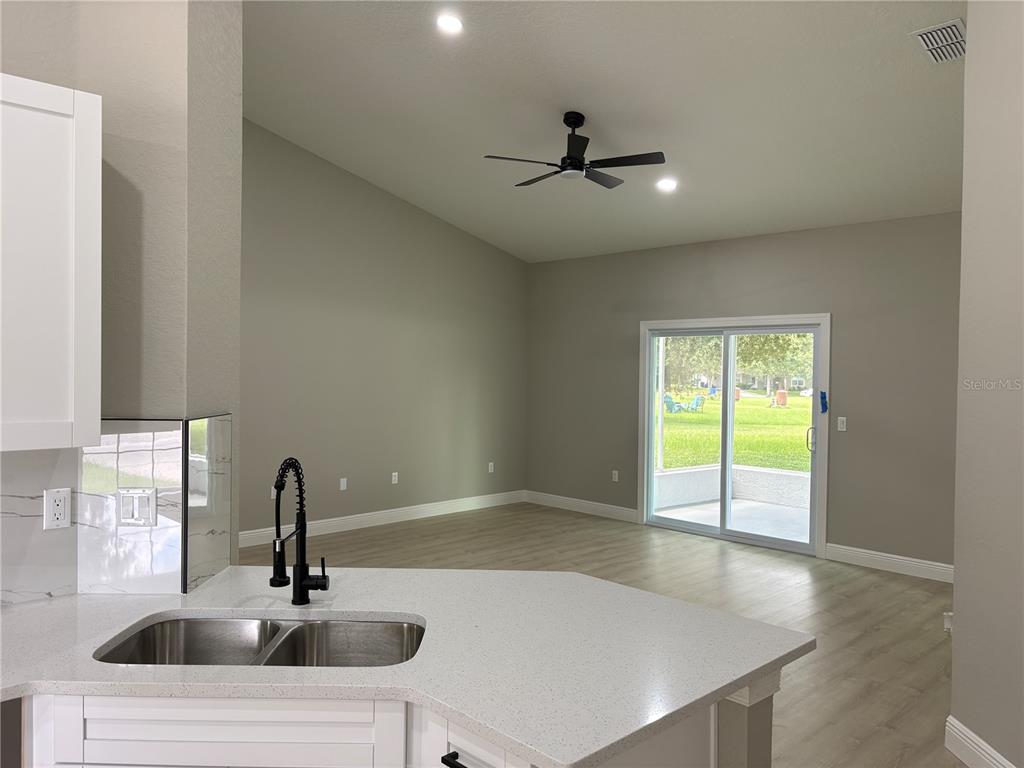 A kitchen sink and countertop overlook an open living area with sliding glass doors — 1415 CRISTO REY PLACE, PLANT CITY, FL