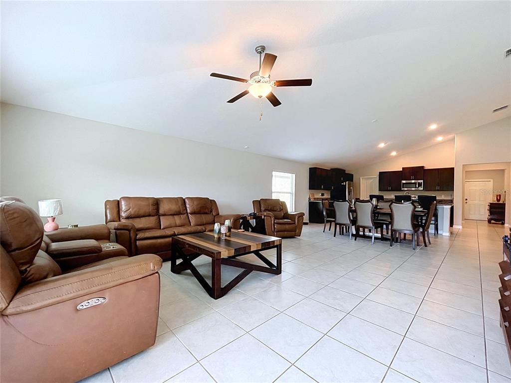 An open-concept living and dining area features tile flooring, leather furniture, and dark wood cabinetry — 1565 COLDING DRIVE, RUSKIN, FL