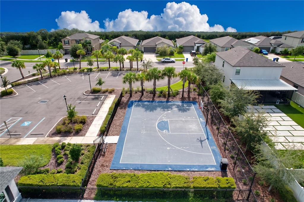 An aerial view shows a fenced basketball court next to a parking lot and houses — 1565 COLDING DRIVE, RUSKIN, FL