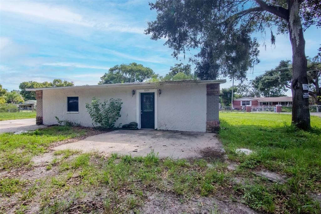 A single-story white house with a flat roof, a front door, and a concrete patio — 1009 MERCER LOOP, PLANT CITY, FL