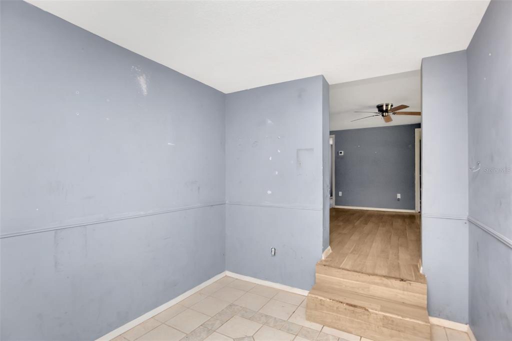 A room with blue walls and tile flooring leads up wooden steps to another room — 1009 MERCER LOOP, PLANT CITY, FL