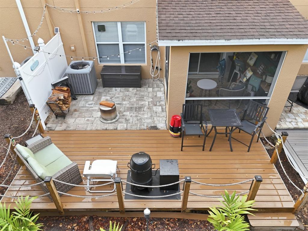 An elevated wooden deck overlooks a paved patio area with a fire pit and grill — 15150 PIPING PLOVER COURT UNIT 103, NORTH FORT MYERS, FL